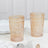 Decorative glass tumblers in soft pink hue on a marble surface.