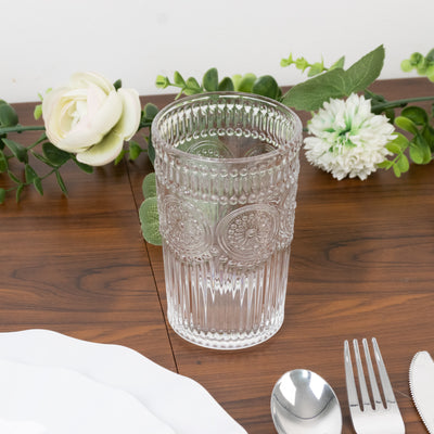 Decorative clear glass tumbler on a wooden table with floral accents.