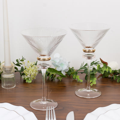 Elegant glass martini glasses with gold accents on a wooden table.