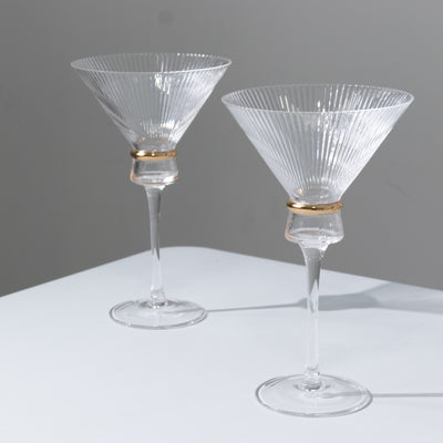 Elegant crystal martini glasses with ribbed design and gold accents.