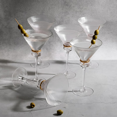 Elegant glass martini glasses with olives on a textured surface.