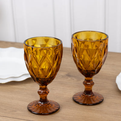 Amber glass goblets with diamond pattern on a wooden table.