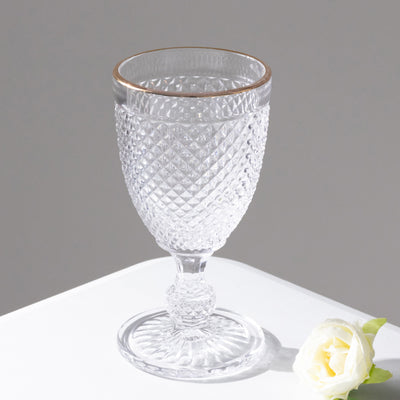 Crystal goblet with diamond pattern and gold rim on a white background