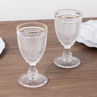 Crystal goblets with gold rims on a wooden table.