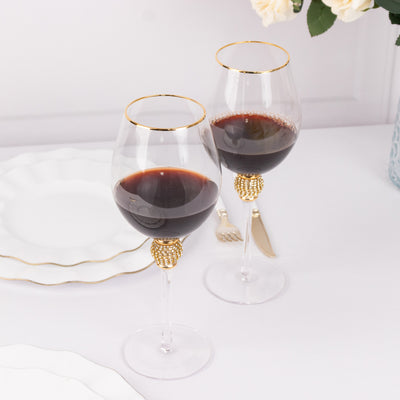 Elegant wine glasses with gold rim and decorative base, filled with red wine.
