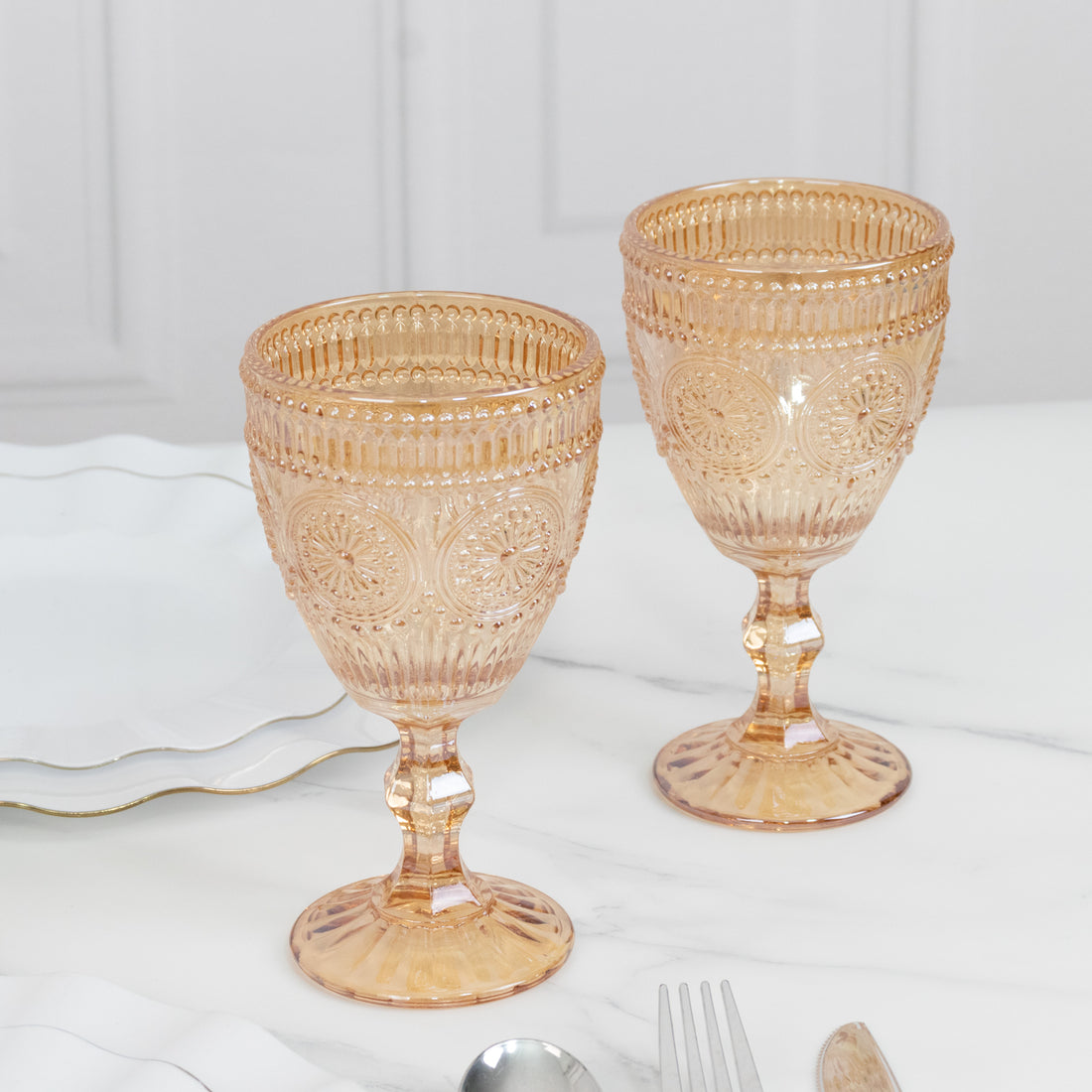 Elegant pink vintage goblets on a marble table setting.