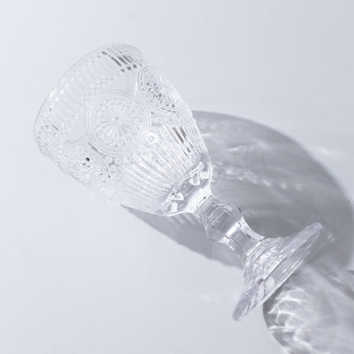 Clear decorative glass goblet with intricate design on plain background