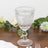 Clear embossed glass goblet on a wooden table with floral accents.