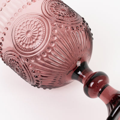 Decorative pink glass goblet with intricate patterns and a stylish stem.