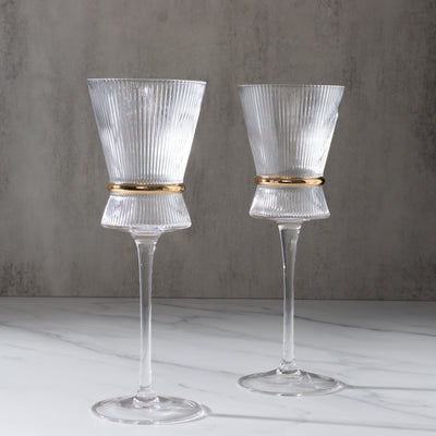 Elegant ribbed glassware set with gold accents on a marble surface.