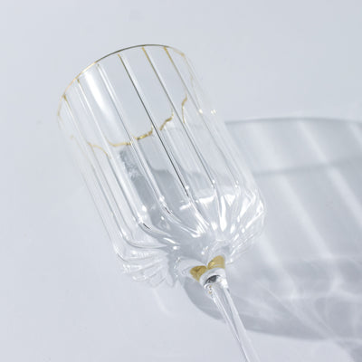 Elegant crystal glass with gold rim and ribbed design.