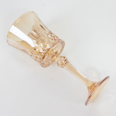 Elegant crystal wine glass in soft peach color, showcasing intricate cut design.