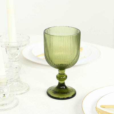 Green ribbed glass goblet on white table setting with gold-rimmed plates