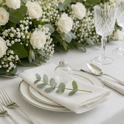 Elegant white wedding table setting with roses, greenery, and crystal glassware