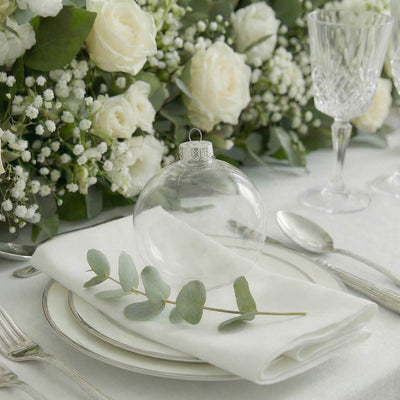 Elegant white wedding table setting with roses and glass ornament