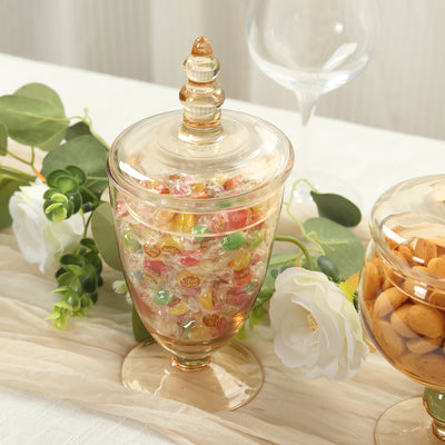 Glass candy jar filled with colorful sweets on a table with decor.