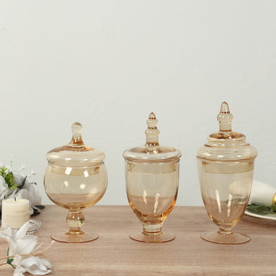 Set of three elegant amber glass jars with lids, perfect for decor or storage.