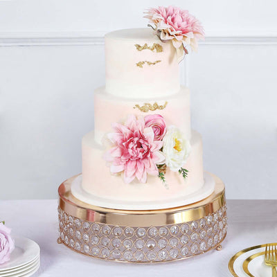 Elegant three-tier wedding cake adorned with pink flowers and gold accents.