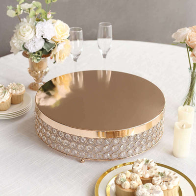 Elegant round cake stand with crystal accents and a reflective gold surface.