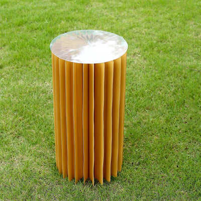 Modern yellow pleated stool with a metallic top on grass