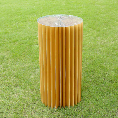 Foldable paper stool in vibrant yellow on green grass.