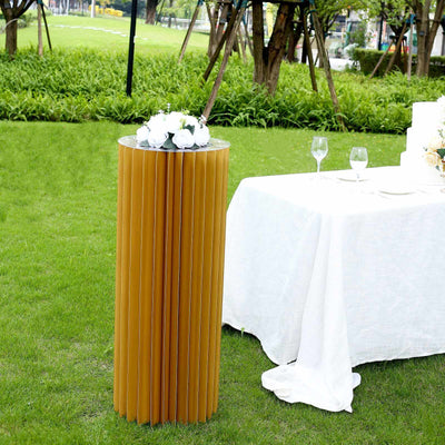 Modern cylindrical table with decorative flowers in outdoor setting.