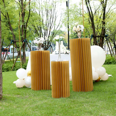 Decorative golden paper columns in an outdoor garden setting with floral arrangements.