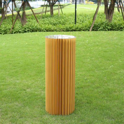 Yellow ribbed outdoor side table with a silver top, set on a grassy lawn.
