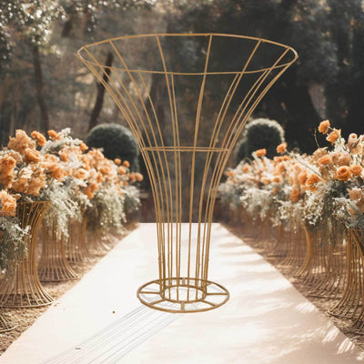 Gold wire flower stand surrounded by floral arrangements in an outdoor setting.
