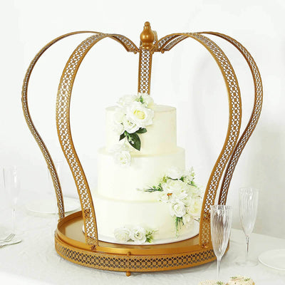Gold crown cake stand with white floral accents and a three-tiered cake.