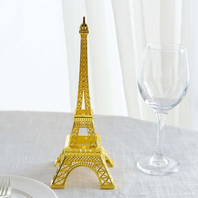 Gold Eiffel Tower replica on a table with a wine glass.