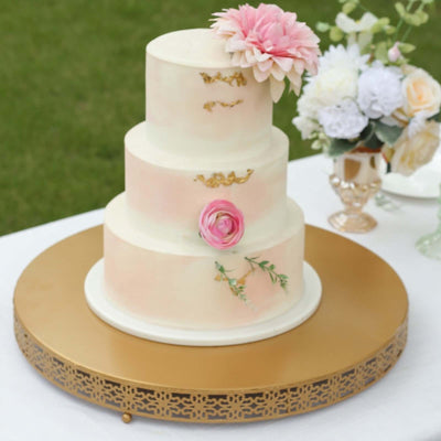 Elegant three-tier cake decorated with flowers on a gold stand.