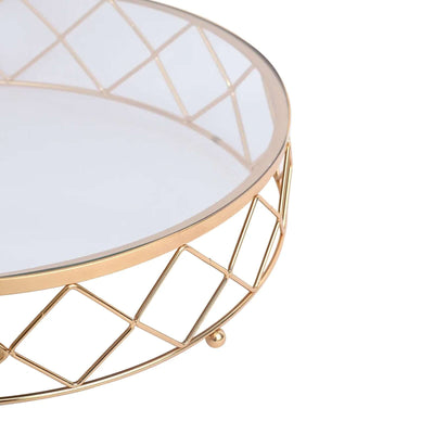 Gold geometric coffee table with glass top and decorative base.