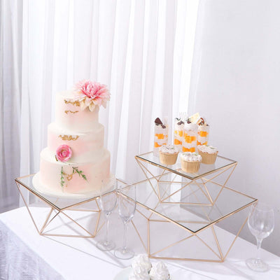 Elegant wedding cake with cupcakes and desserts on stylish glass stands.