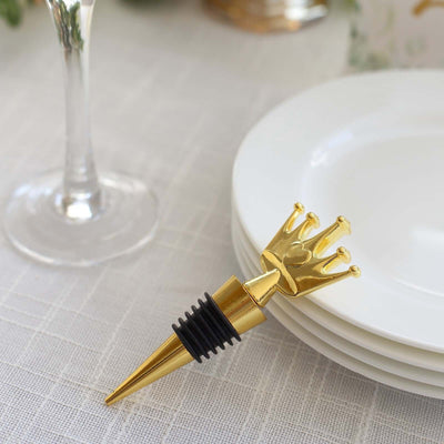 Gold crown wine bottle stopper on a table next to white plates.