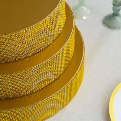 Three stacked yellow cake tiers with decorative trim on a table.