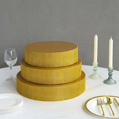 Gold tiered cake boxes on a table with candles and glassware.
