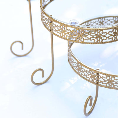 Gold metal plant stand with intricate design and curved legs.