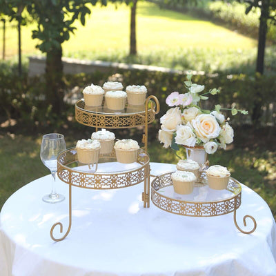 Gold cupcake stand with cupcakes and floral arrangement outdoors.