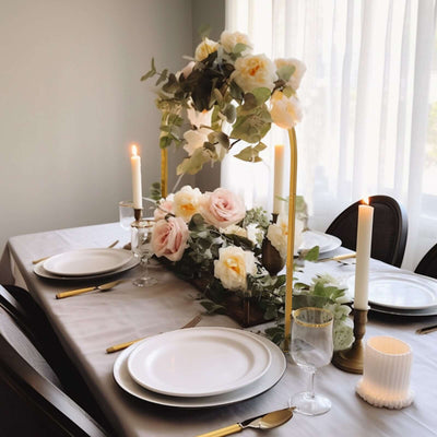 Elegant dining table set with floral centerpiece, candles, and fine tableware.