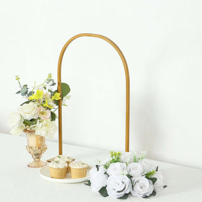 Gold arch display stand with flowers and cupcakes arranged elegantly.