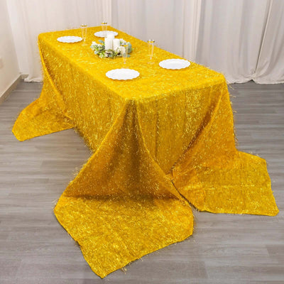Bright yellow tablecloth with shimmering fringe on a styled dining table.