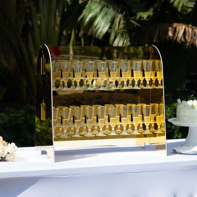 Elegant gold champagne tower display at an outdoor event.