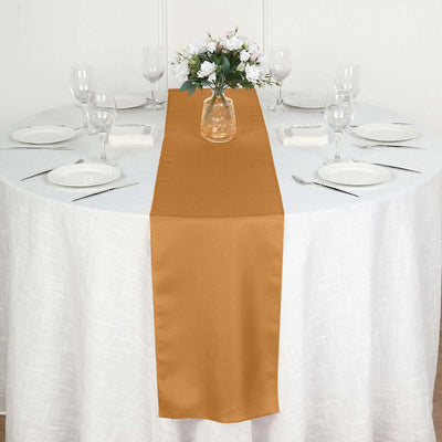 Elegant gold table runner on a white dining table with floral centerpiece.