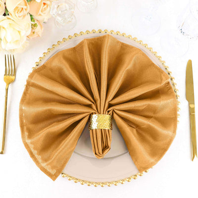 Elegant gold napkin folded on a plate, surrounded by tableware.