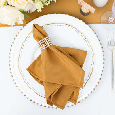 Brown napkin elegantly folded on a decorative plate with a floral centerpiece.