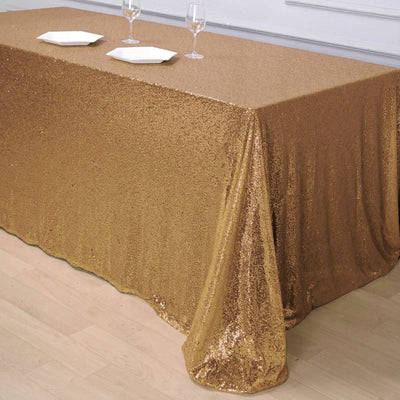 Gold sequin tablecloth draping elegantly over a table with plates and glasses.
