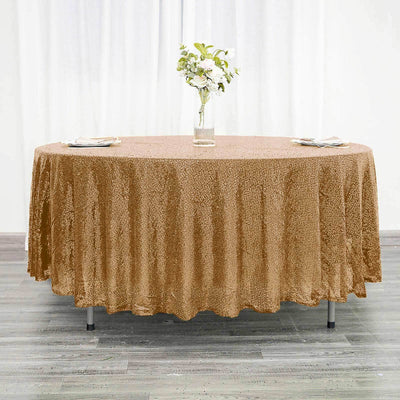 Round gold sequin tablecloth on a round table with a floral centerpiece.