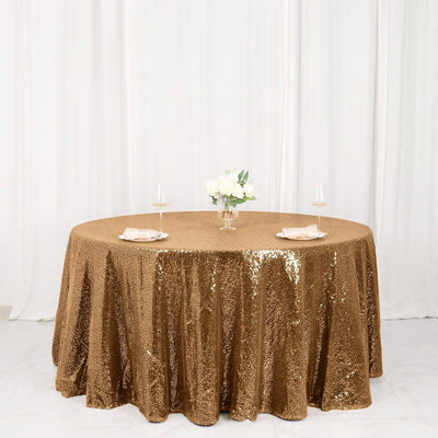 Gold sequin tablecloth on round table with floral centerpiece and glassware.