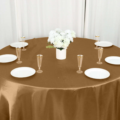 Elegant table setting with gold tablecloth, floral centerpiece, and glassware.